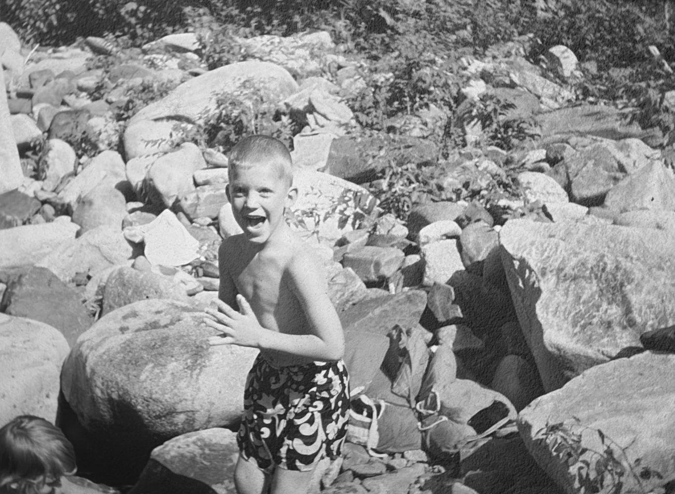 Jonathan as a boy, laughing among the rocks by the water
